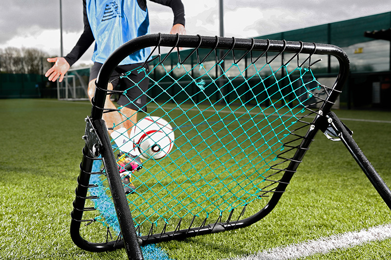 Footballer using a football rebounder in a training session