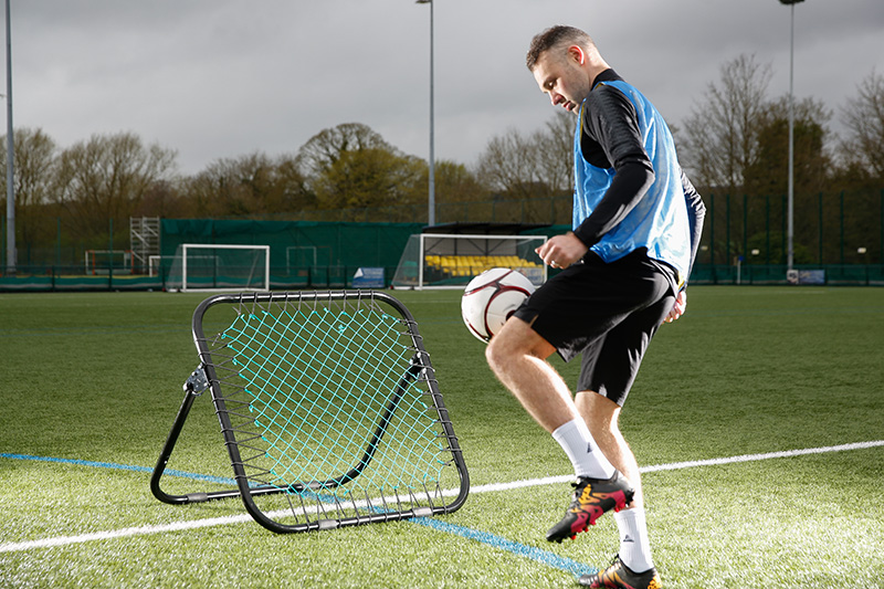 Football rebounder drills - player using a rebounder at training