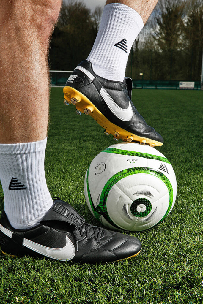 Man wearing football grip socks and boots with left foot on a football