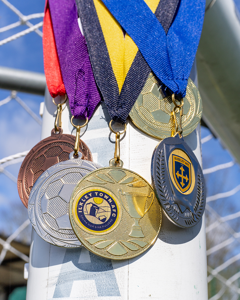 A selection of medals hanging off a football goal