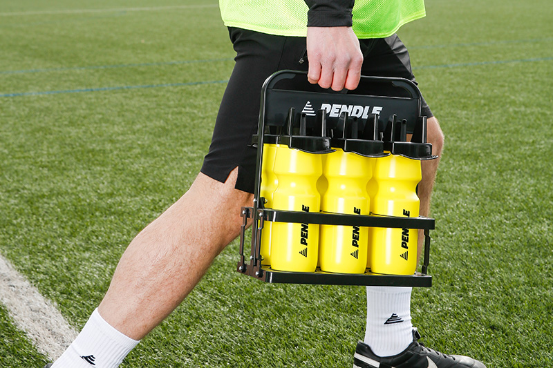 Football player walking onto the pitch with a bottle carrier holding 6 water bottles