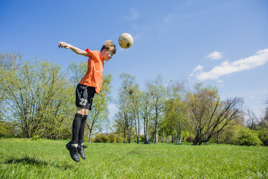 Young football player heading a football