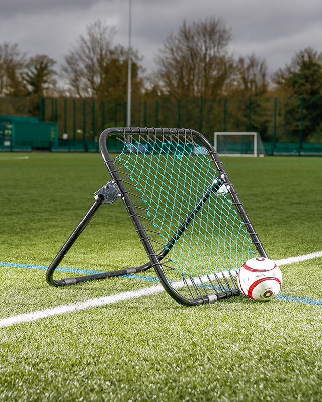 Football rebounder and football on the pitch