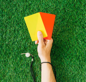 Football referee holding a red and yellow card