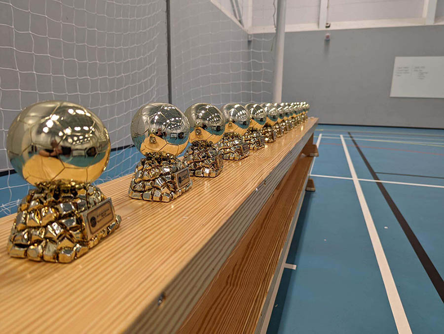 Line of Pendle Football Trophies on a bench in a sports hall