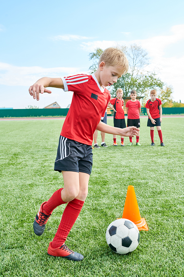 Child controlling a football round a cone