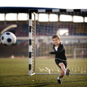 Boy kicking a football in a goal