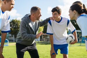 Coach Talking to Young Football Players Before a Game