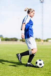 Female football player dribbling a football