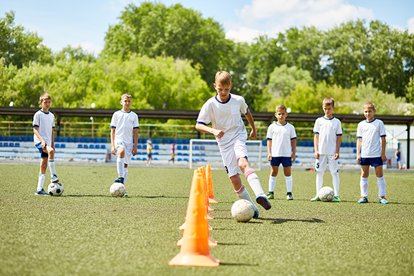 Child dribbling a football through cones