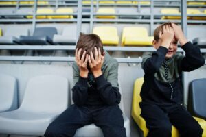 Two junior players sat in football stalls with their heads in their hands
